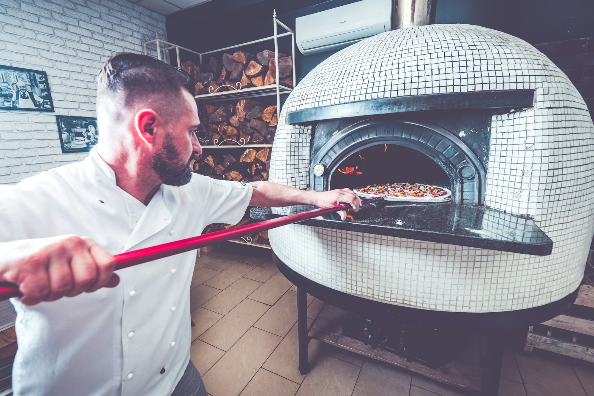 Bearded man chef preparing pizza at local business